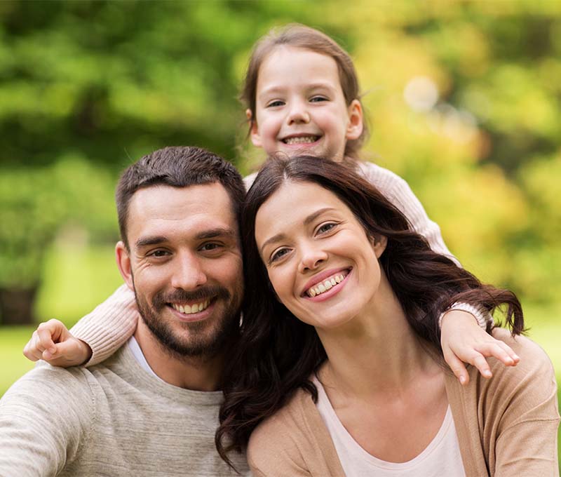 A family of four posing for a photo, with the father on the left, mother in the middle, and two children on the right.