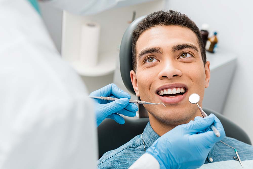 A dental professional performing a tooth extraction on a patient, with the patient smiling and looking upwards.
