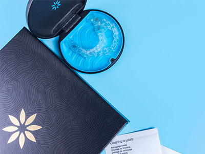A blue and black toothbrush with a tube of toothpaste, placed on top of an open magazine or brochure.
