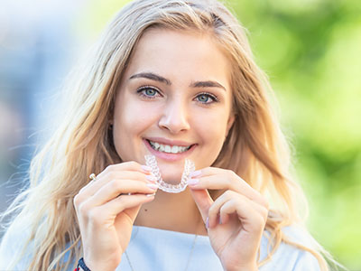 Smiling woman holding a toothbrush with braces, posing for the camera.