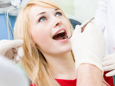 A woman in a dental chair receiving oral care, with medical personnel attending to her.